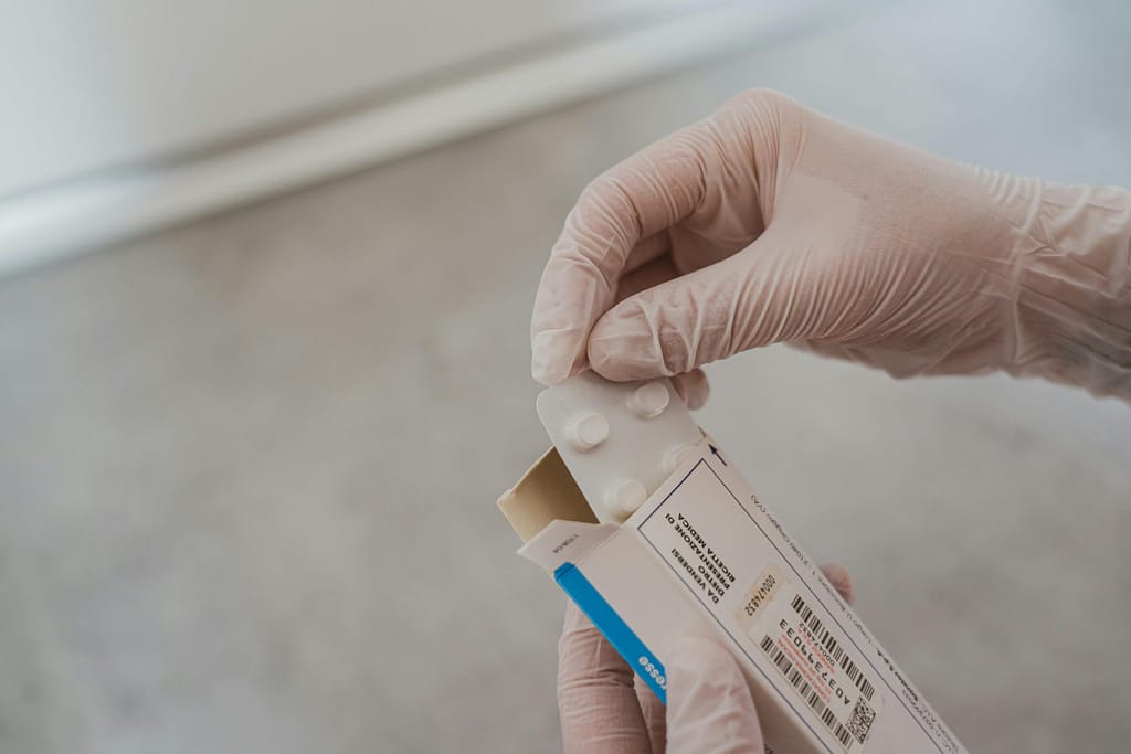 Close-up of hands in gloves handling medication blister pack, ensuring safety and hygiene in healthcare.